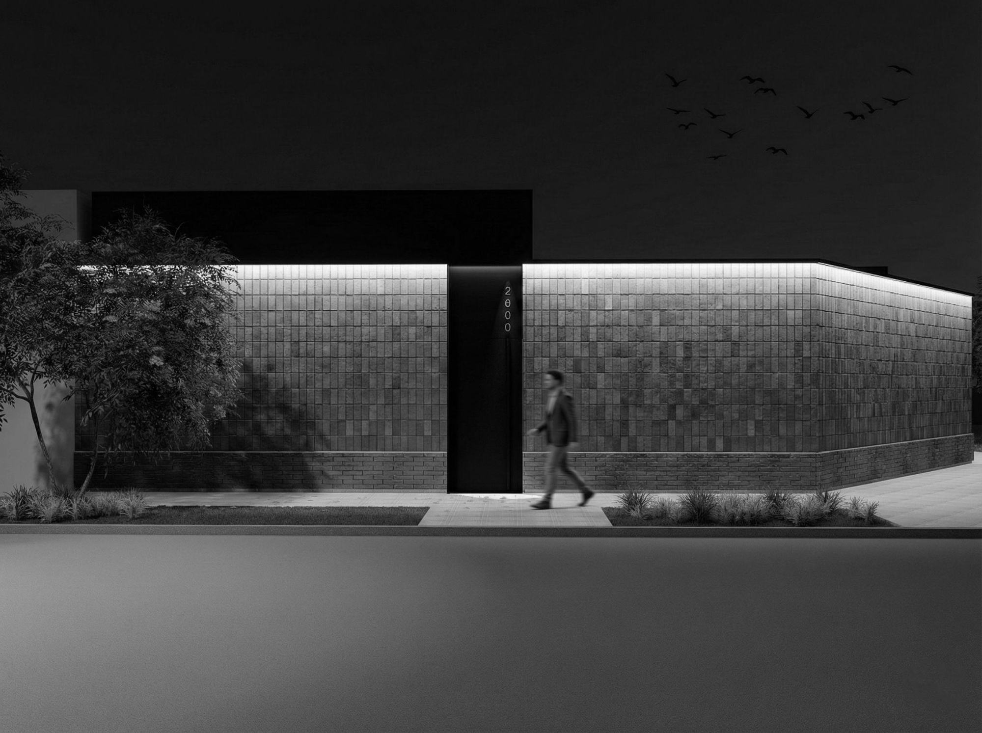 Colombia 509: fachada nocturna de ladrillo con iluminación rasante, en blanco y negro